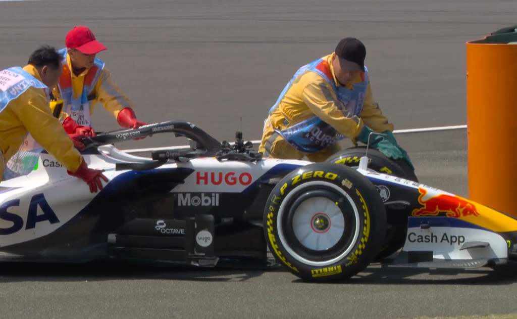 Arvid Lindblad's car getting rolled of the track by stewards Arvid Lindblad's Red Bull stationary on the straight before Turn 14 at the Shanghai International Circuit, with marshals in attendance wearing insulated gloves as smoke is reported in the cockpit during Free Practice 1 at the 2025 Chinese Grand Prix.