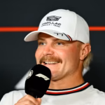 Valtteri Bottas speaking at a Formula 1 press conference wearing a white Cadillac Formula 1 Team cap with number 77