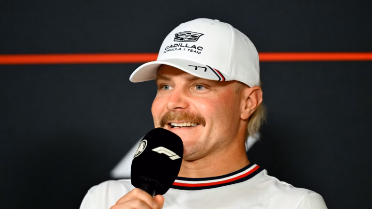 Valtteri Bottas speaking at a Formula 1 press conference wearing a white Cadillac Formula 1 Team cap with number 77